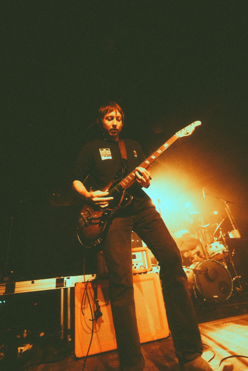 Geoff Nelson playing guitar under orange stage light