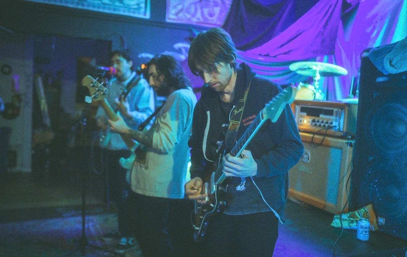 Geoff Nelson playing guitar onstage under blue light